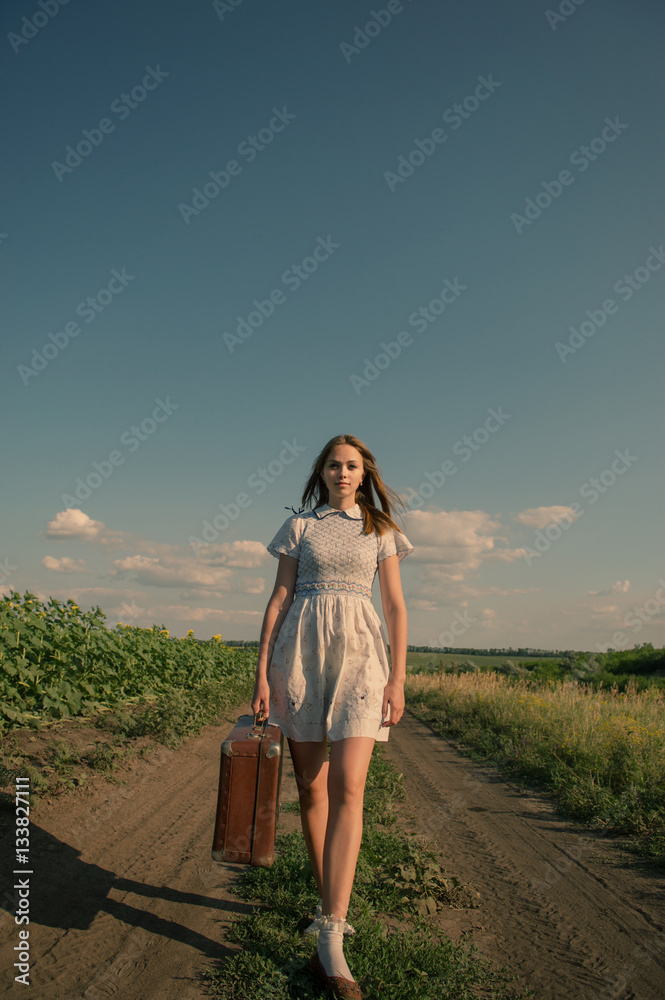 Obraz premium Cute girl goes on a dirt road in field