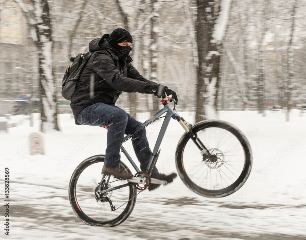 A man rides a bicycle in snowy weather A man rides a bicycle in snowy weather