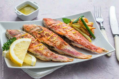 Plate of fried small fish red mullet and lemon, close view photo