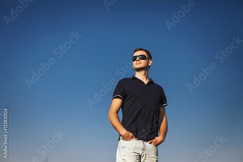 man stands proudly and looks into the distance over blue sky