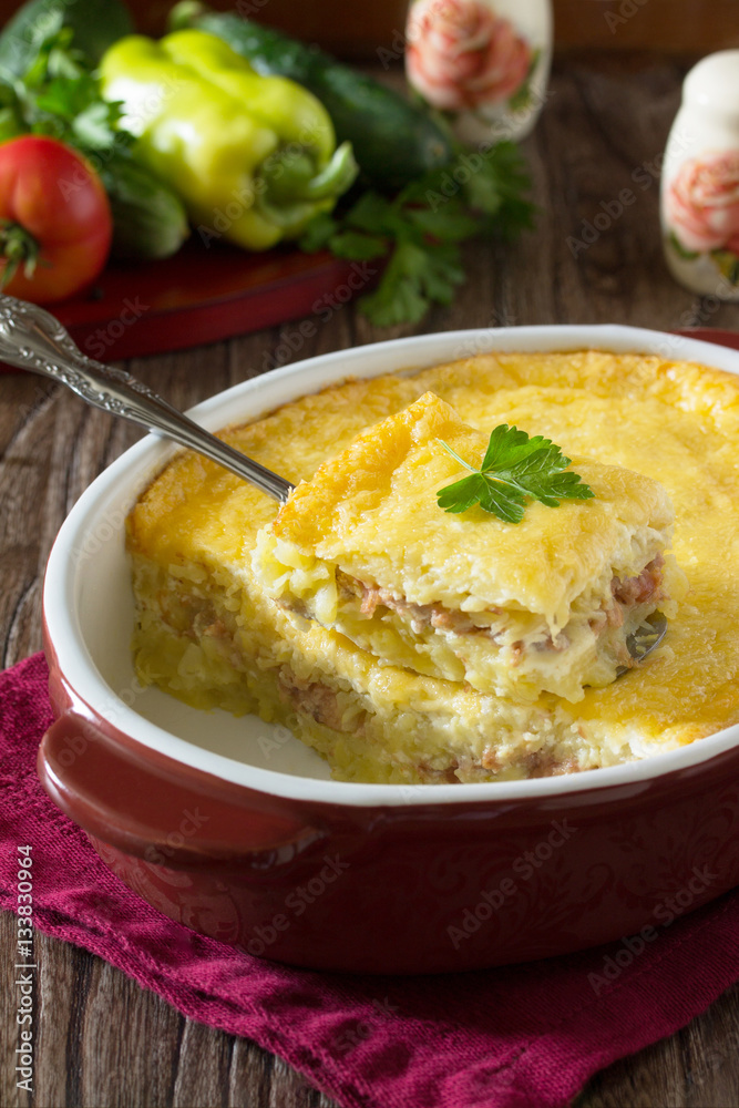 Casserole with potatoes, meat and cheese on a wooden table. Spac