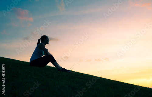 Thoughtful young woman watching the sunset. Peaceful moment's  and thinking concept. 