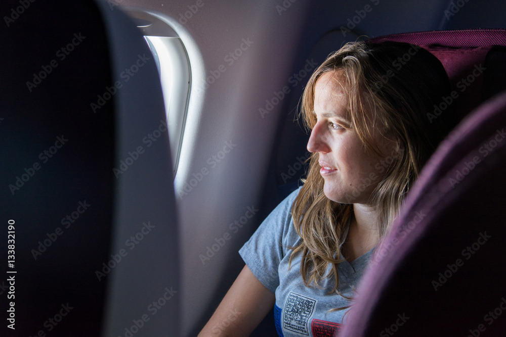 Attractive young brunette looking through airplane window.