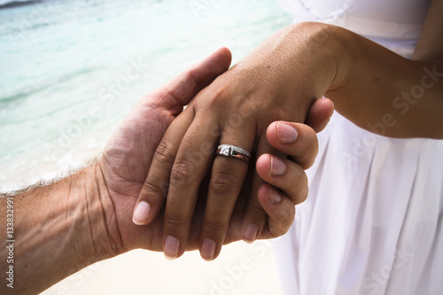 Man holding woman's hand with wedding ring