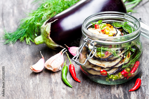 Grilled  sliced eggplant with chili in glass jar on rustic table