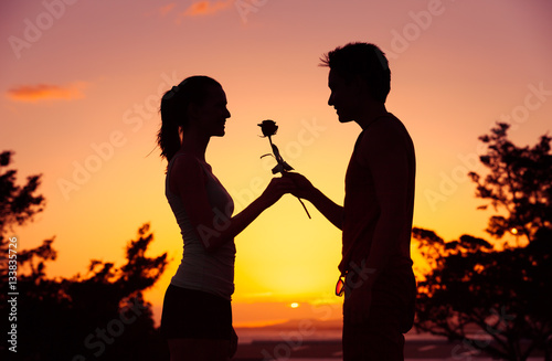 Man giving woman a rose flower. 