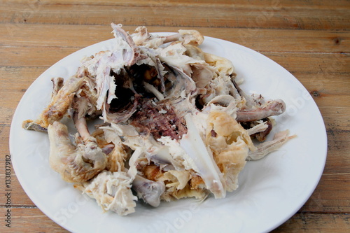 Roast chicken carcass remains on a plate on a wooden table