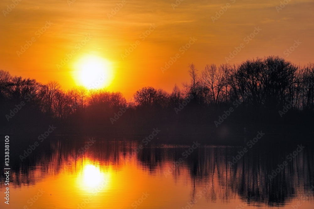 Sunset creating a mirror reflection in Pickerel Lake in Pratt's Wayne Woods Forest Preserve in Wayne, Illinois.