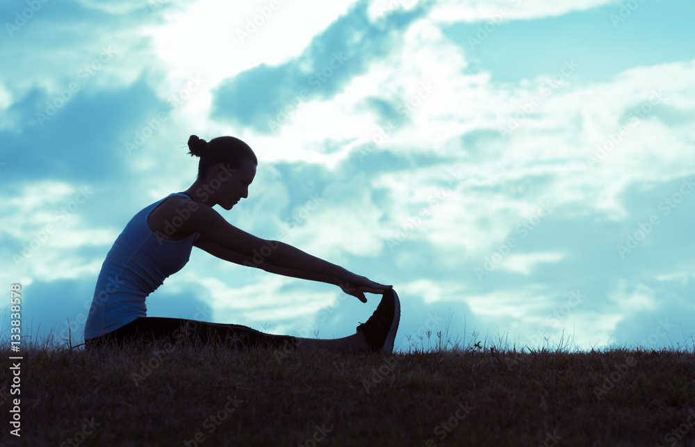 Female runner doing leg stretches in the park. Female runner doing leg stretches in the park.