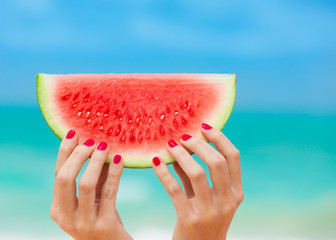 Colorful summer days concept. Hand holding up slice of watermelon.