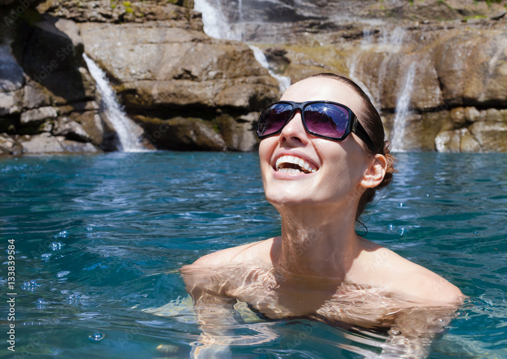 Happy woman relaxing in a natural spring.