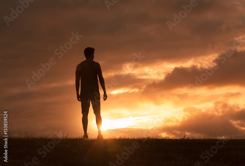 Man standing facing a beautiful sunset.  photo
