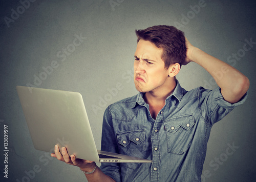 Funny clueless guy having troubles with laptop. Complicated technology