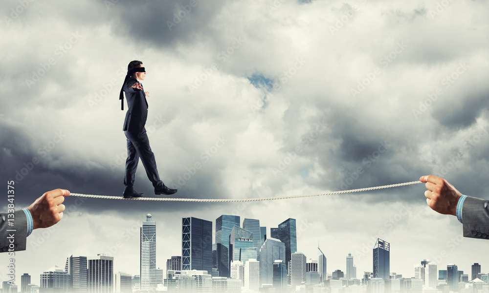 Business concept of risk support and assistance with man balancing on rope Business concept of risk support and assistance with man balancing on rope