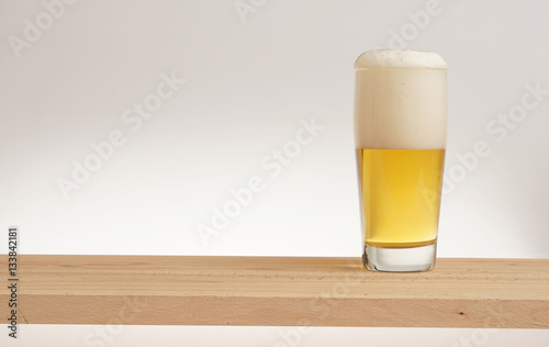 Glass of light beer on a wooden board.