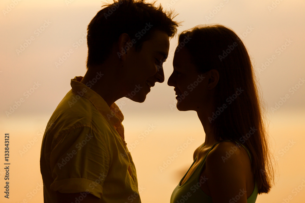 Young couple kissing against a beautiful sunset. 