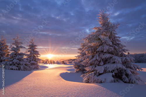 Wunderschöner Sonnenaufgang an einem kalten Wintertag im Erzgebirge mit einer kleinen Holzhütte im Hintergrund photo
