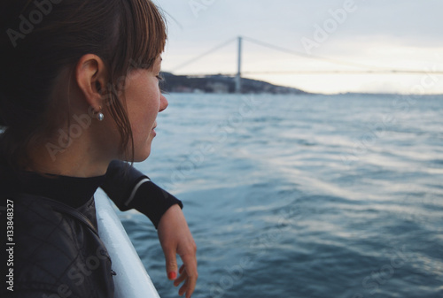 Photography Young woman looking away from boat passing bridge