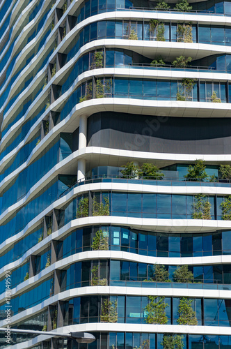 Green skyscraper building with curvy organic forms and plants gr photo