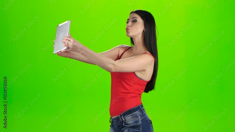 Brunette making photo using a tablet pc. Green screen studio Brunette making photo using a tablet pc. Green screen studio