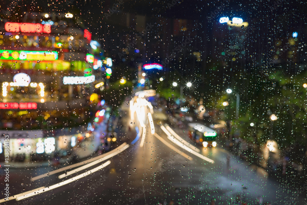 Rain water drops on a window glass after the rain with cityscape and street view on background