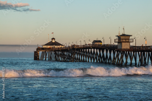 The Imperial Beach fishing pier in San Diego, California at dawn with crashing waves.