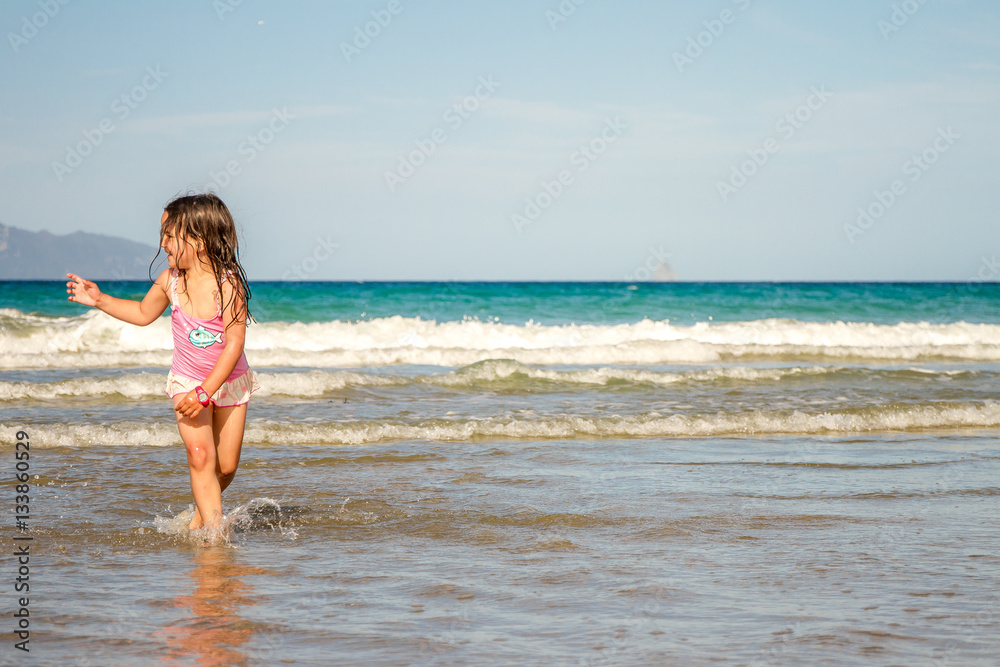 young happy child girl having fun on sand beach, sea background