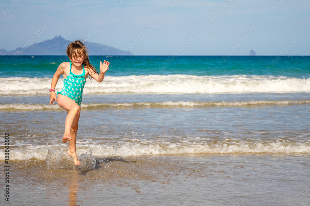young happy child girl having fun on sand beach, sea background young happy child girl having fun on sand beach, sea background