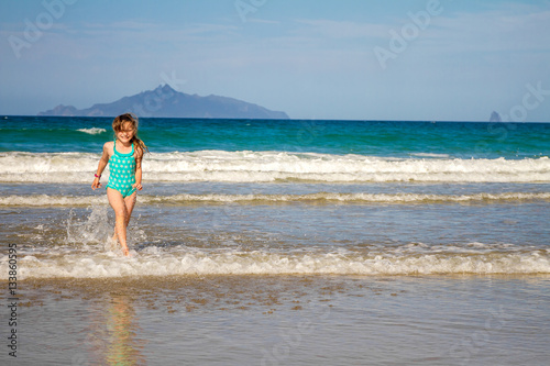 young happy child girl having fun on sand beach, sea background