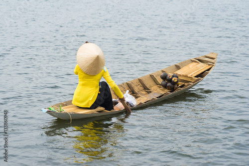 Vietnamese woman rowing wooden boat on river photo