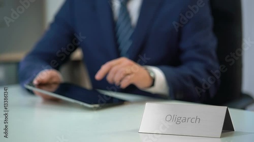 Wealthy oligarch using tablet pc, considering investment in business project photo