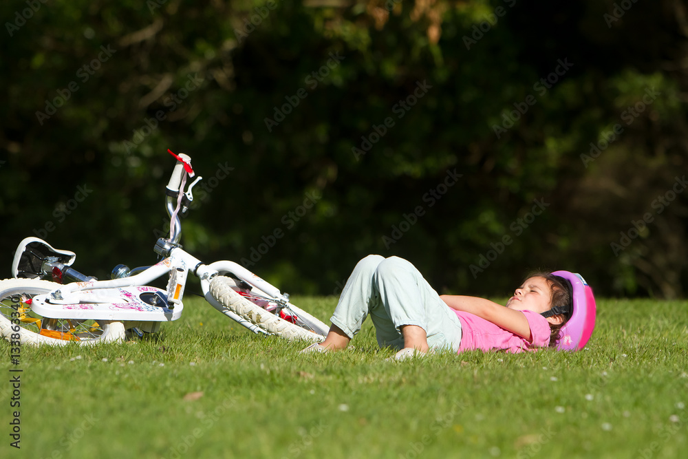 Φωτογραφία young caucasian child girl sleeping near her bike on natural bac