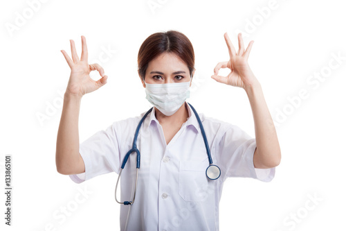 Young Asian female doctor with mask show OK with both hands.