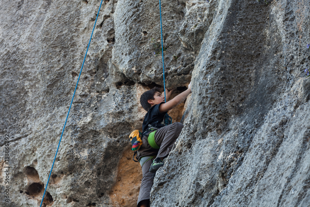 Boy climbing on a limestone wall