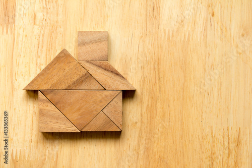 Tangram puzzle in home shape on wooden background (Concept for d