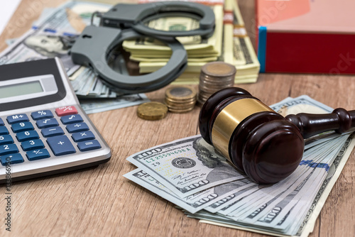 Law gavel with handcuffs, dollars and books as background, close up.