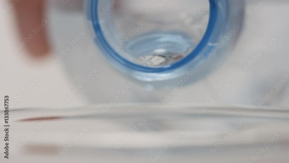 SLOW MOTION: Human hand pours a clear water from a plastic bottle SLOW MOTION: Human hand pours a clear water from a plastic bottle