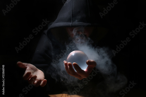 Tela man in a black hood with cristal ball