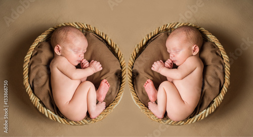 Two naked newborn baby baskets sleeping in the fetal position