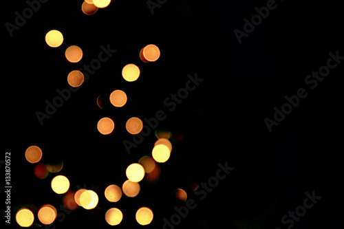 golden abstract blinking blurred Christmas tree lights bokeh on black background, festive holiday