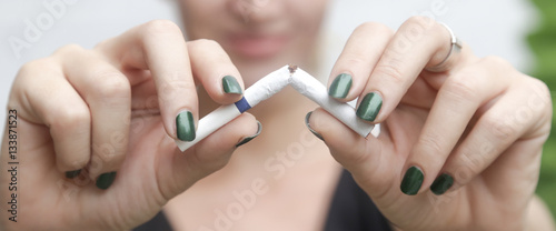 Young woman breaking down cigarette to pieces. - quit smoking concept