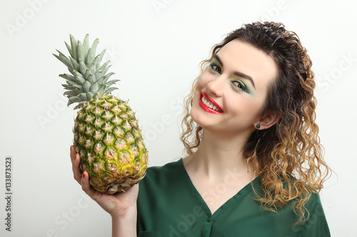 Cheerful girl model holding a pineapple.