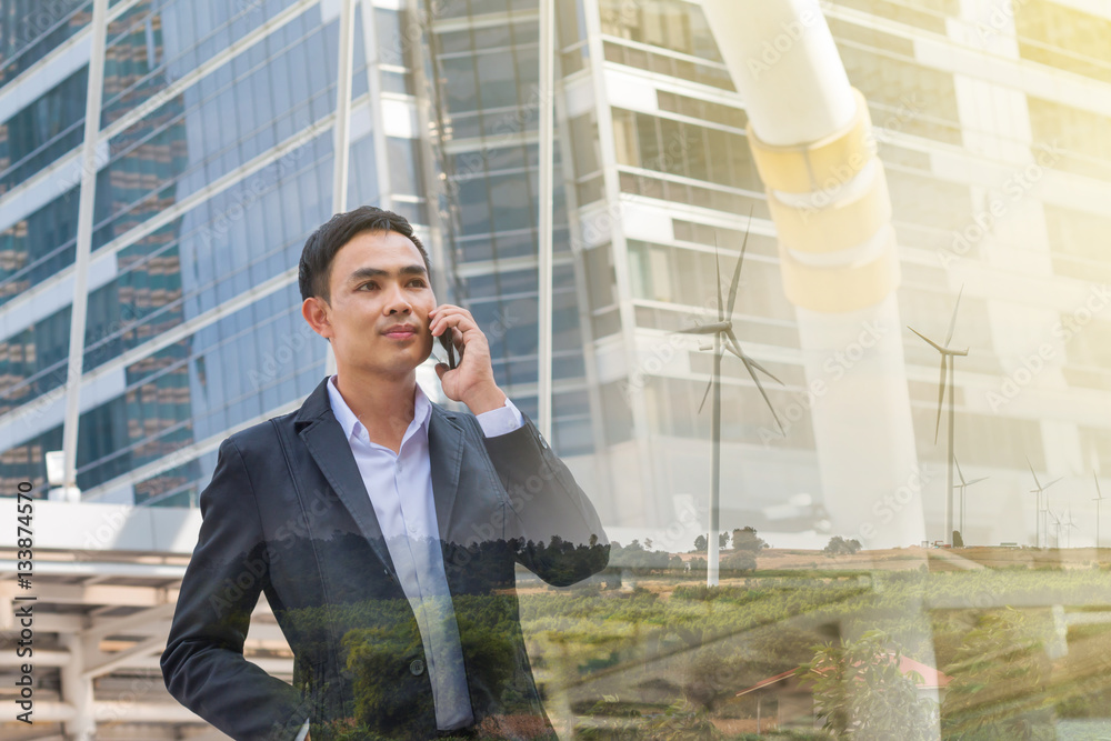 portrait of businessman talking on smartphone with wind turbine