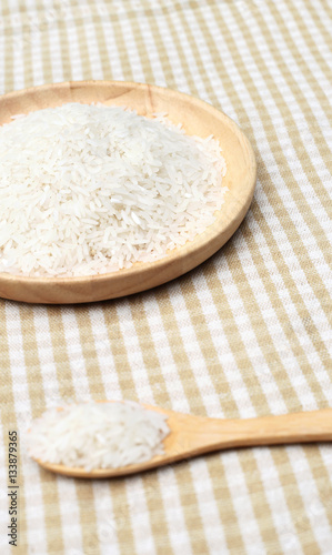 Uncooked white rice on wooden plate and spoon 