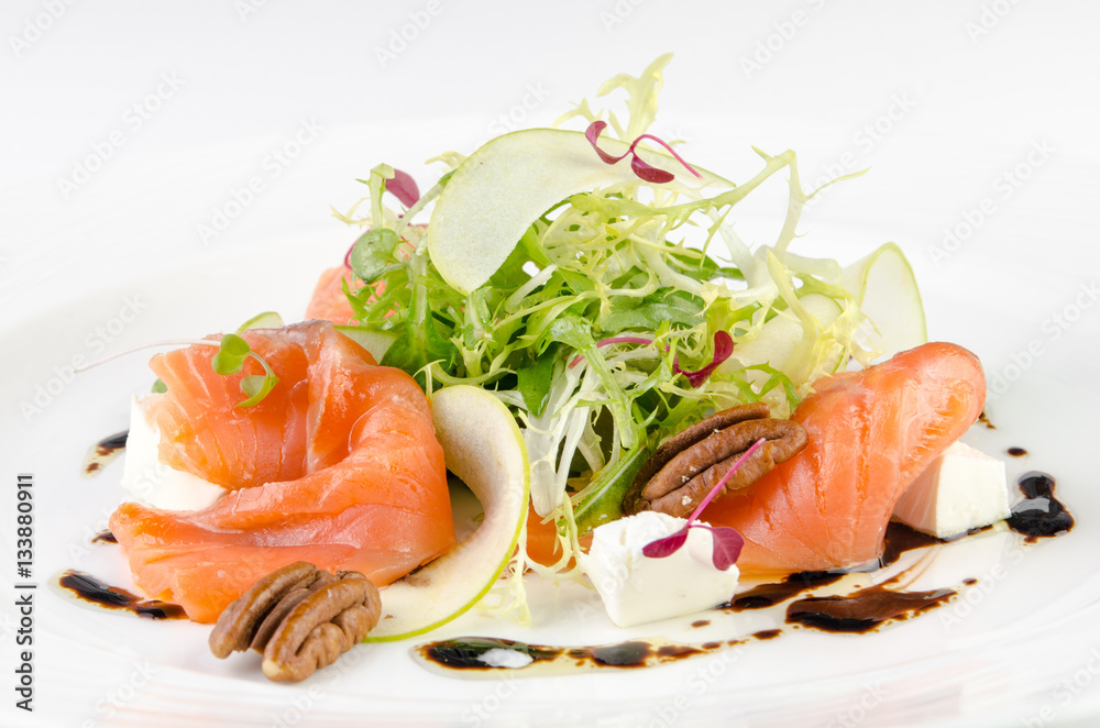 Marinated salmon with feta cheese, green apple, pecan and soy sauce on a plate on a white background, closeup Marinated salmon with feta cheese, green apple, pecan and soy sauce on a plate on a white background, closeup