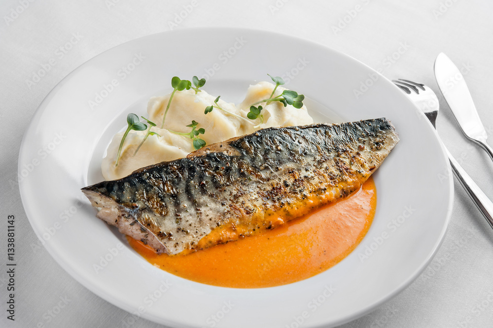 Golden mackerel with orange sauce and mashed potatoes lies on a Golden mackerel with orange sauce and mashed potatoes lies on a