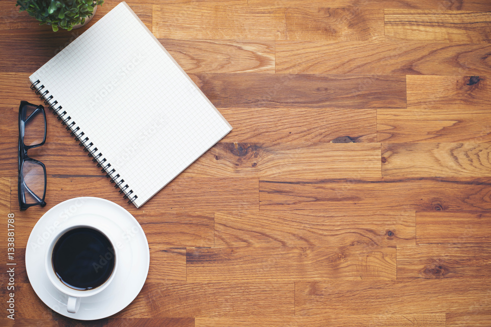Coffee cup and notebook lens on wooden table background Coffee cup and notebook lens on wooden table background