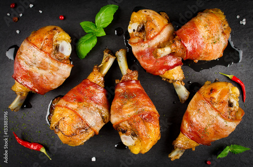 Bacon wrapped chicken legs on a black background