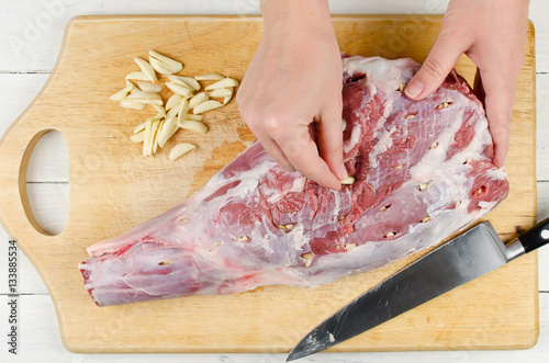 Raw leg of lamb with garlic on a cutting Board