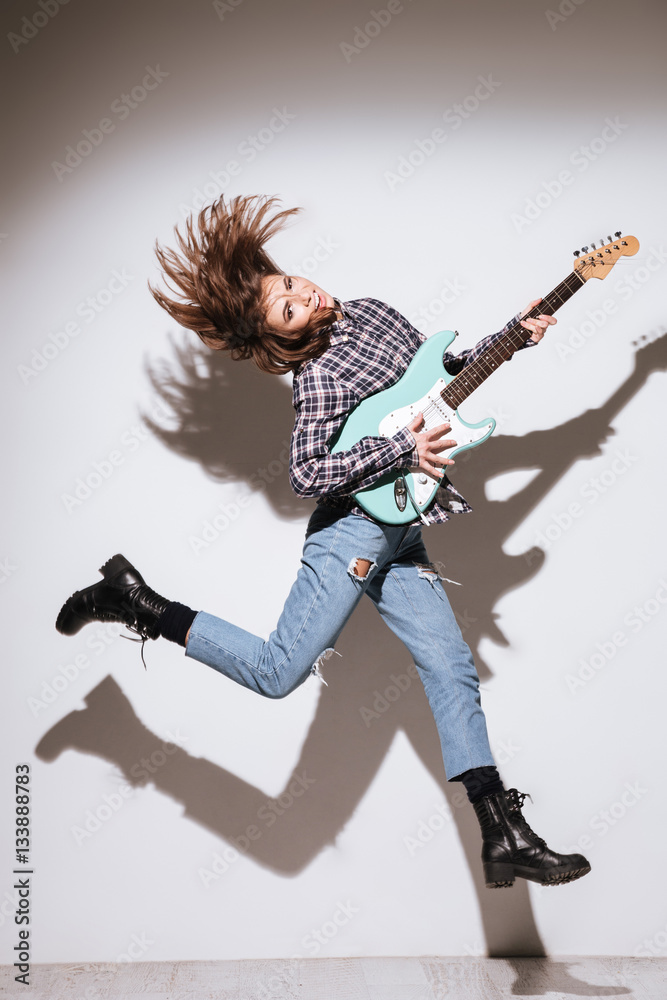 Lady holding guitar and jumping